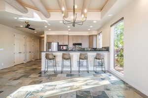 Kitchen with a chandelier, beam ceiling, a breakfast bar, freestanding refrigerator, and a peninsula