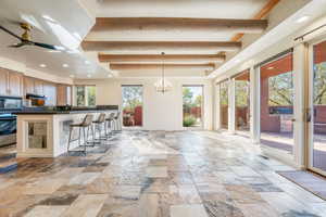 Kitchen with a breakfast bar area, recessed lighting, beamed ceiling, hanging light fixtures, and brown cabinetry