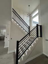 Staircase with wood finished floors and a chandelier