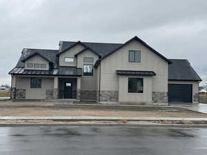 View of front of home with roof with shingles, a standing seam roof, stone siding, and a metal roof