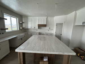 Kitchen with white cabinetry, a textured ceiling, recessed lighting, and a kitchen island