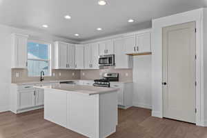 Kitchen with white cabinets, appliances with stainless steel finishes, decorative backsplash, recessed lighting, and light wood-type flooring
