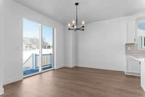 Unfurnished dining area with a chandelier and light wood-type flooring
