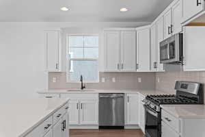 Kitchen featuring appliances with stainless steel finishes, white cabinetry, backsplash, and recessed lighting
