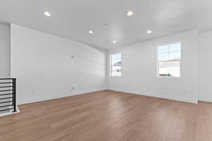 Unfurnished room with a textured ceiling, light wood-style floors, and recessed lighting