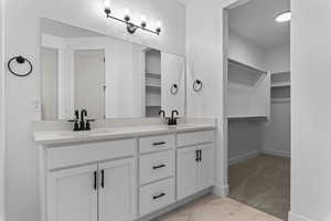 Full bath with a walk in closet, double vanity, and light marble finish flooring