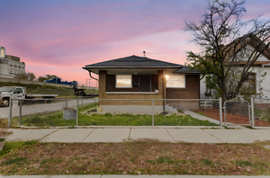 Bungalow-style home featuring a gate, a fenced front yard, brick siding, and a porch