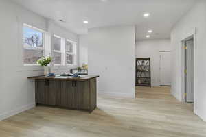 Kitchen with recessed lighting, light wood-style floors, a peninsula, an office area, and dark brown cabinets