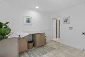 Washroom with electric dryer hookup, washer hookup, light tile patterned floors, crown molding, and recessed lighting
