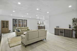 Living room with recessed lighting, beverage cooler, and light wood-type flooring