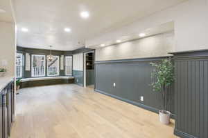 Unfurnished living room with light wood finished floors, wainscoting, recessed lighting, and built in features