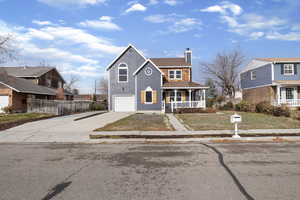 View of front of house with a porch, a chimney, driveway, a garage, and a residential view