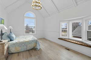 Bedroom featuring beam ceiling, a chandelier, high vaulted ceiling, and light wood finished floors