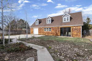 View of front facade featuring a shingled roof and concrete driveway