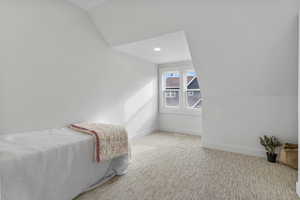 Bedroom featuring vaulted ceiling, light carpet, and recessed lighting