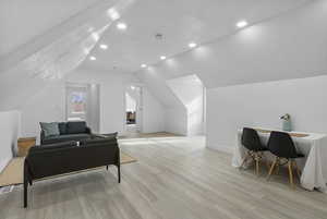 Bedroom with a textured ceiling, light wood-style flooring, lofted ceiling, and recessed lighting