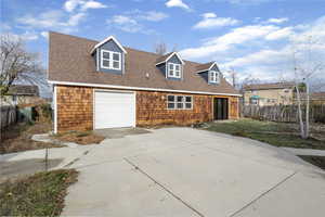 New england style home featuring concrete driveway and a shingled roof