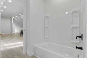 Full bathroom featuring recessed lighting, light wood-type flooring, shower / washtub combination, and vaulted ceiling