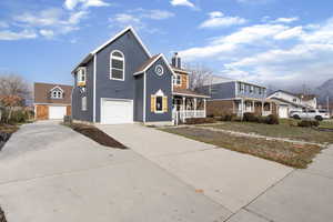 Traditional-style home with a porch, driveway, a chimney, and an attached garage