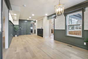 Unfurnished living room featuring light wood finished floors, a chandelier, and recessed lighting