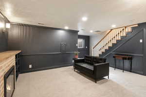 Living room featuring ornamental molding, carpet floors, stairs, a brick fireplace, and recessed lighting
