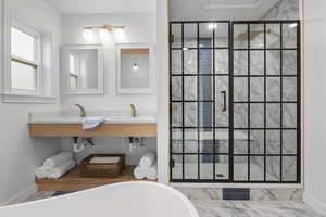 Bathroom with marble finish floors, double vanity, a freestanding tub, and a shower stall