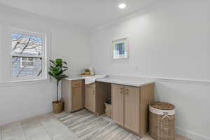 Bar area with light countertops, light tile patterned floors, and ornamental molding