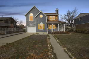 View of front of property featuring a porch, driveway, a chimney, and an attached garage