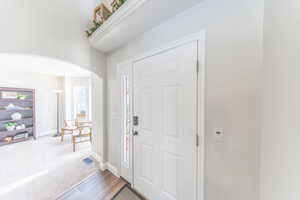 Foyer featuring arched walkways and carpet flooring