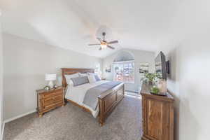 Carpeted bedroom featuring vaulted ceiling and ceiling fan