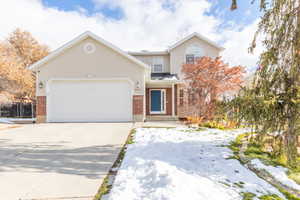View of front of home featuring brick siding, concrete driveway, an attached garage, and stucco siding