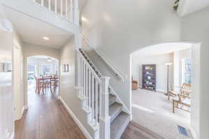 Staircase featuring arched walkways, wood finished floors, healthy amount of natural light, a towering ceiling, and recessed lighting