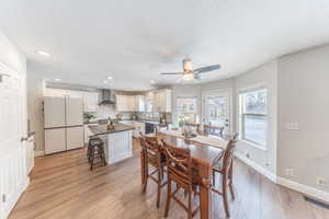 Dining area featuring light wood-style flooring, ceiling fan, recessed lighting, and a textured ceiling