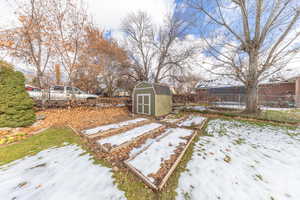 Fenced backyard with a storage unit and a garden