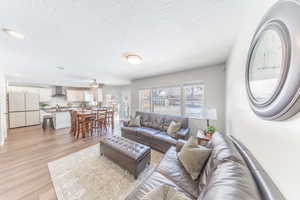 Family room featuring a textured ceiling, light wood-style flooring, a ceiling fan, and recessed lighting