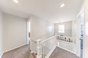 Hallway featuring carpet and an upstairs landing