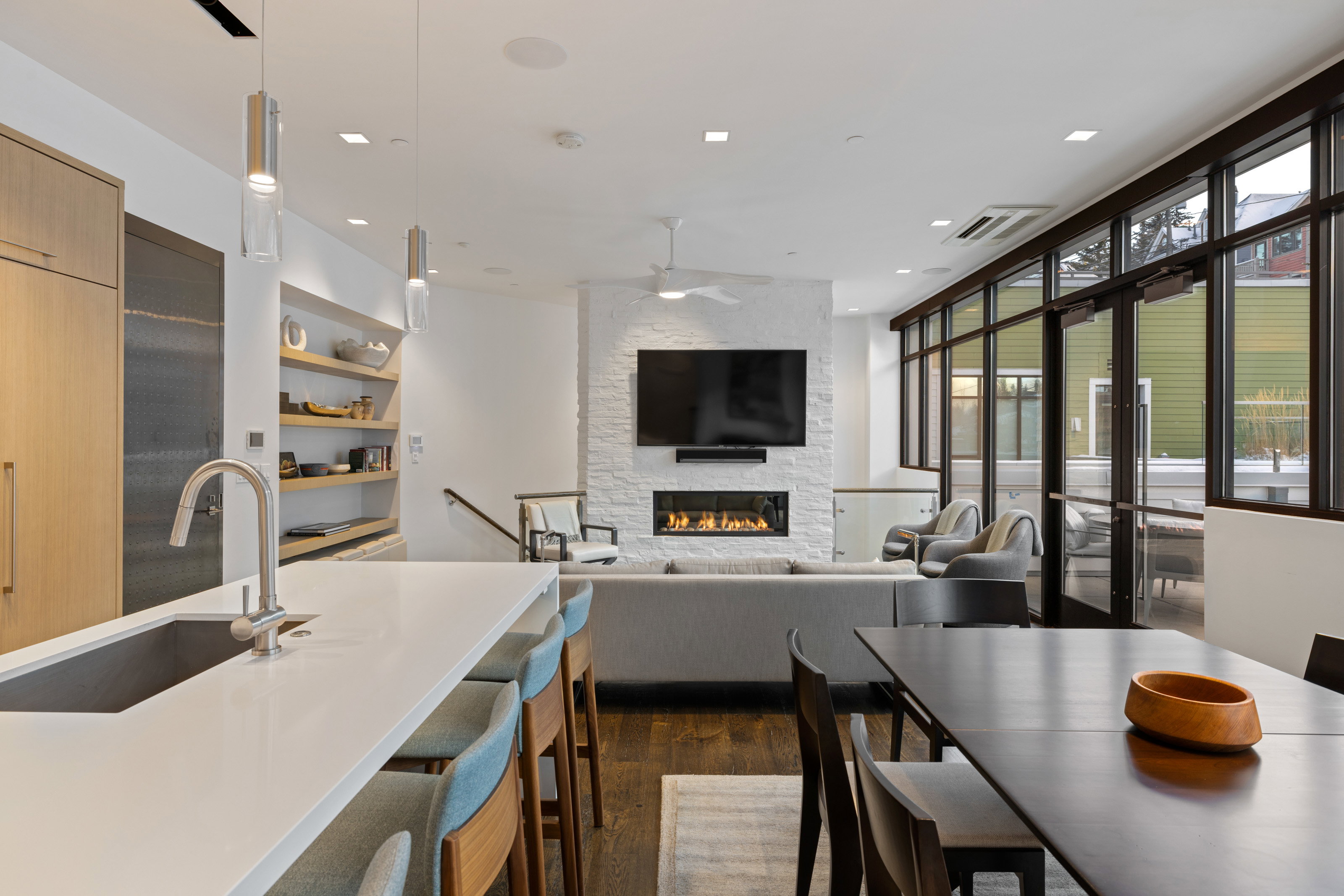 Kitchen featuring a stone fireplace, decorative light fixtures, dark wood-style flooring, ceiling fan, and modern cabinets