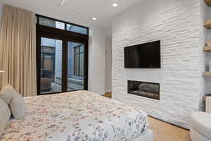 Bedroom with access to outside and a stone fireplace