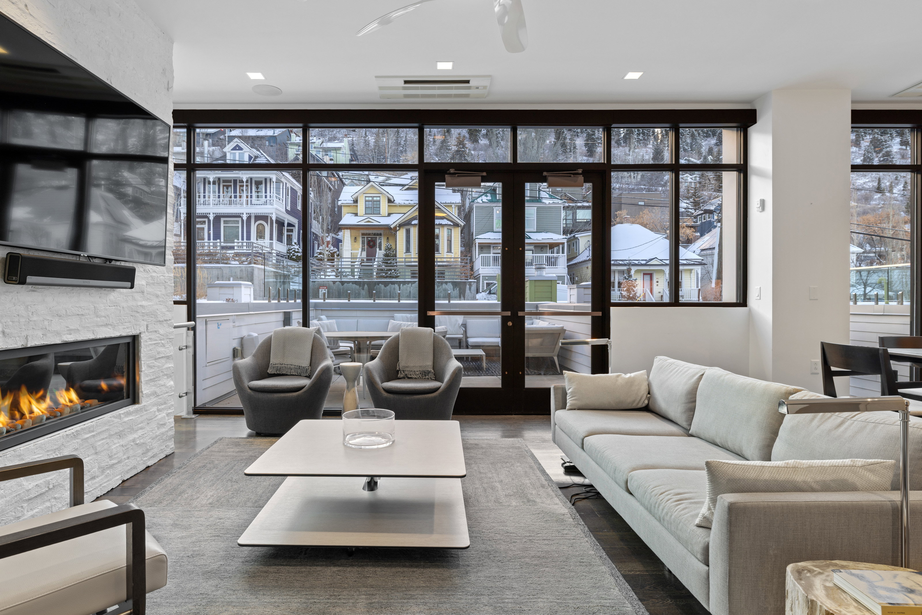 Living room with floor to ceiling windows, a stone fireplace, and wood finished floors