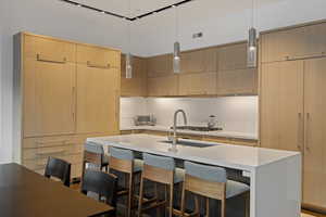 Kitchen with modern cabinets, a breakfast bar, pendant lighting, and light stone countertops