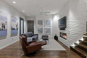 Living room with dark wood-style flooring, a barn door, a fireplace, ceiling fan, and recessed lighting