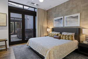 Bedroom featuring access to outside, multiple windows, tile walls, and wood finished floors