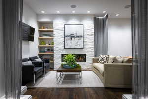 Living area with a fireplace, wood finished floors, built in features, and recessed lighting