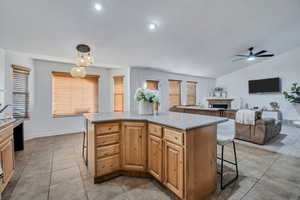 Kitchen with a fireplace, open floor plan, a kitchen breakfast bar, a center island, and decorative light fixtures