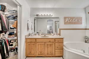 Full bath featuring vanity, a whirlpool tub, a spacious closet, a stall shower, and a textured ceiling
