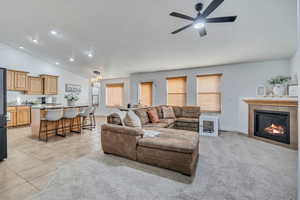 Living room featuring lofted ceiling, a tiled fireplace, plenty of natural light, light tile patterned flooring, and light carpet