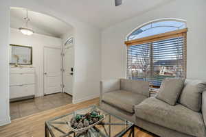 Living area with light wood-style floors, lofted ceiling, and ceiling fan