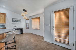 Dining space with light tile patterned flooring, lofted ceiling, and a desk