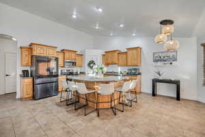 Kitchen with a kitchen island, smart refrigerator, a breakfast bar, high vaulted ceiling, and light stone counters
