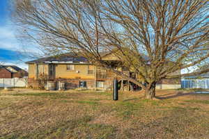 Rear view of house with brick siding, stucco siding, and stairs